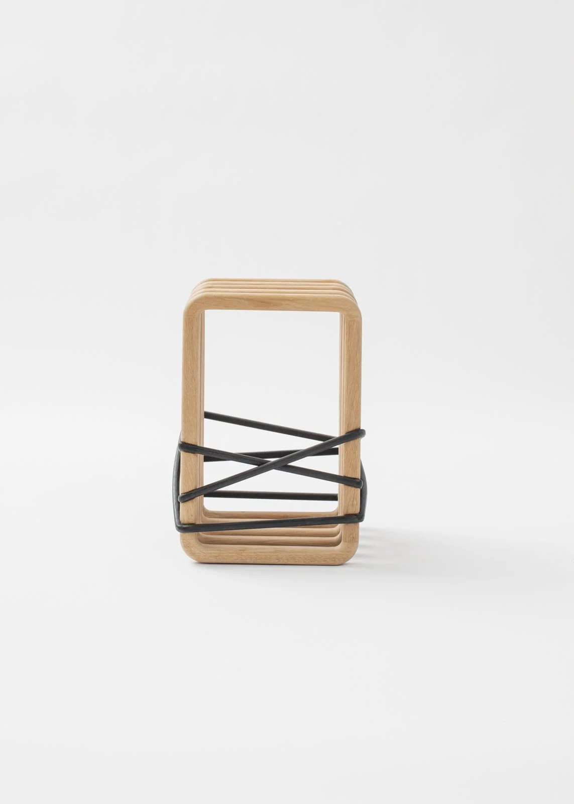 tabouret en bois clair avec des bandes de caoutchouc noir pour le tenir.