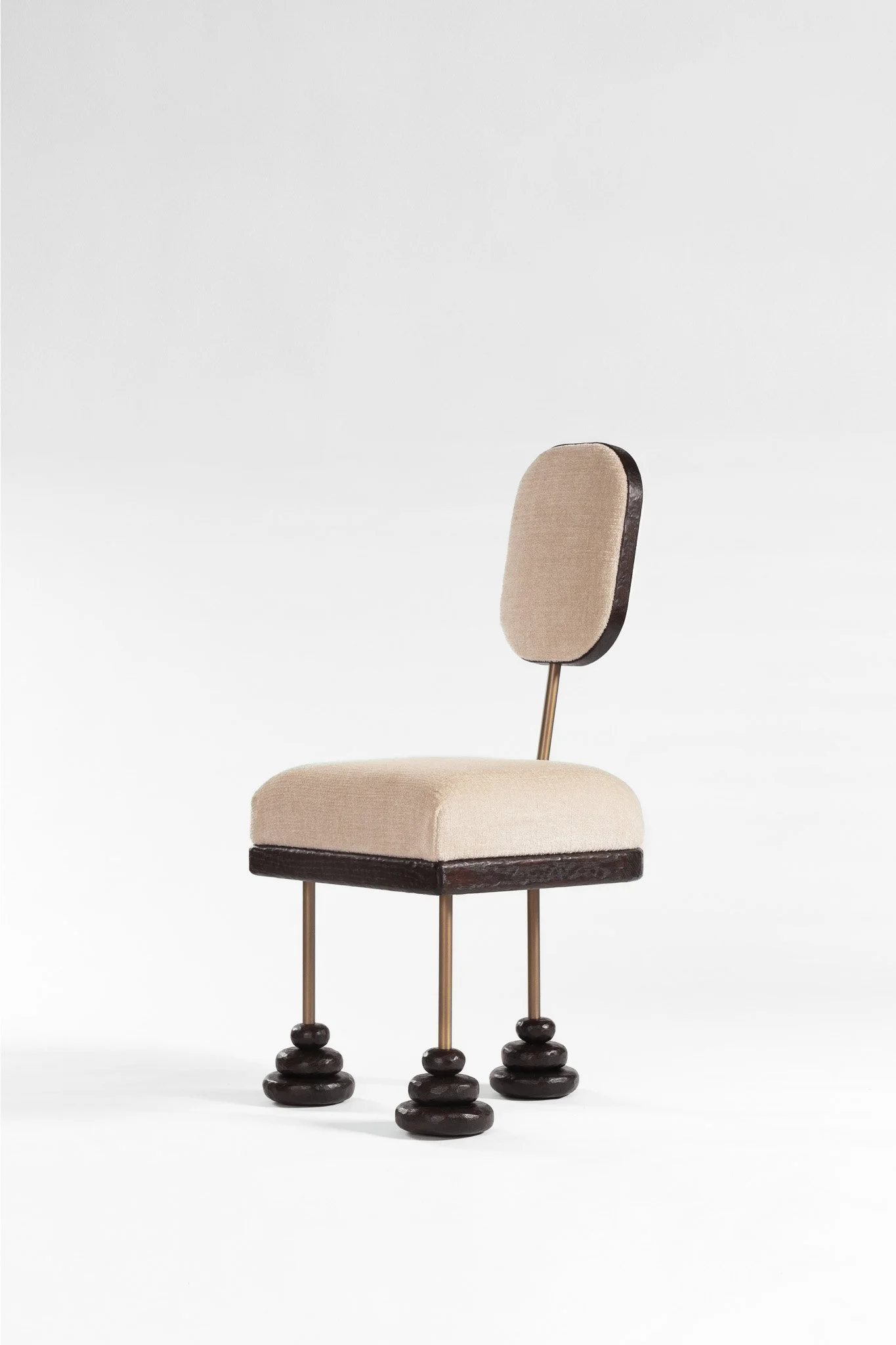 Chaise design avec dossier rembourré beige, pieds en métal with accents en bois sculpté en forme de pierres.