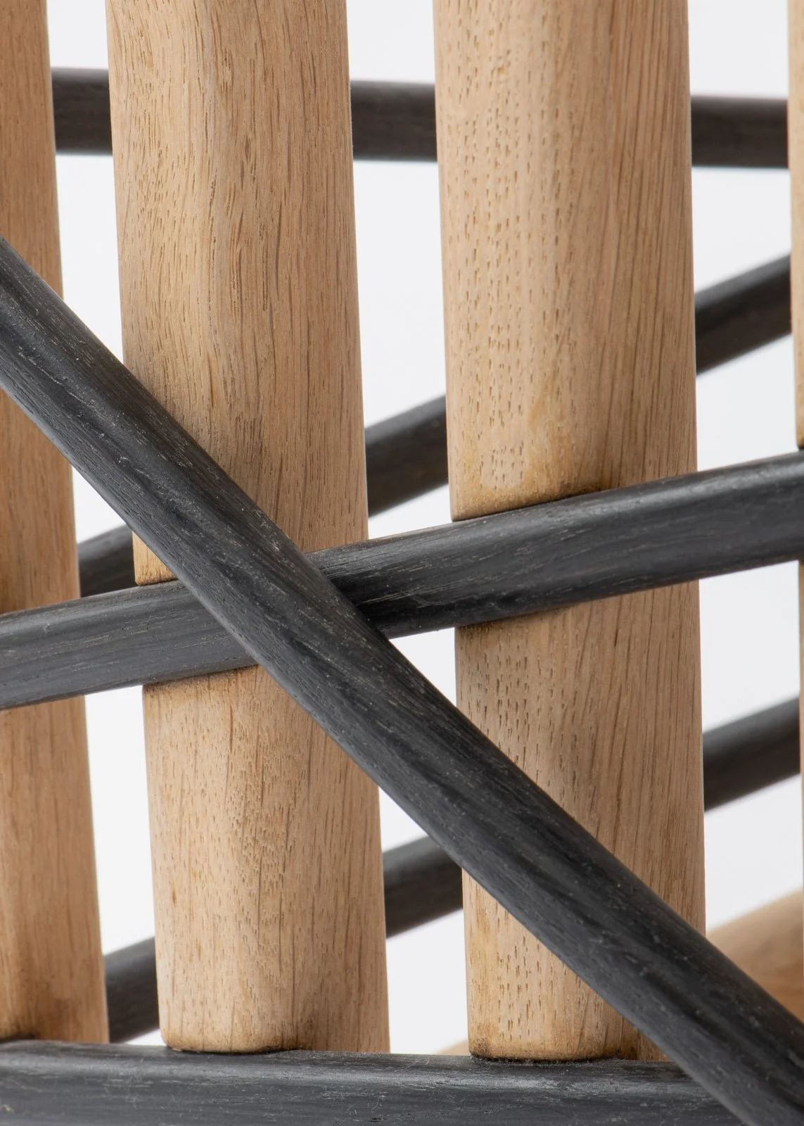 Zoom sur une structure en bois avec des barres en métal noir, formant une grille ou un meuble avec un design moderne.