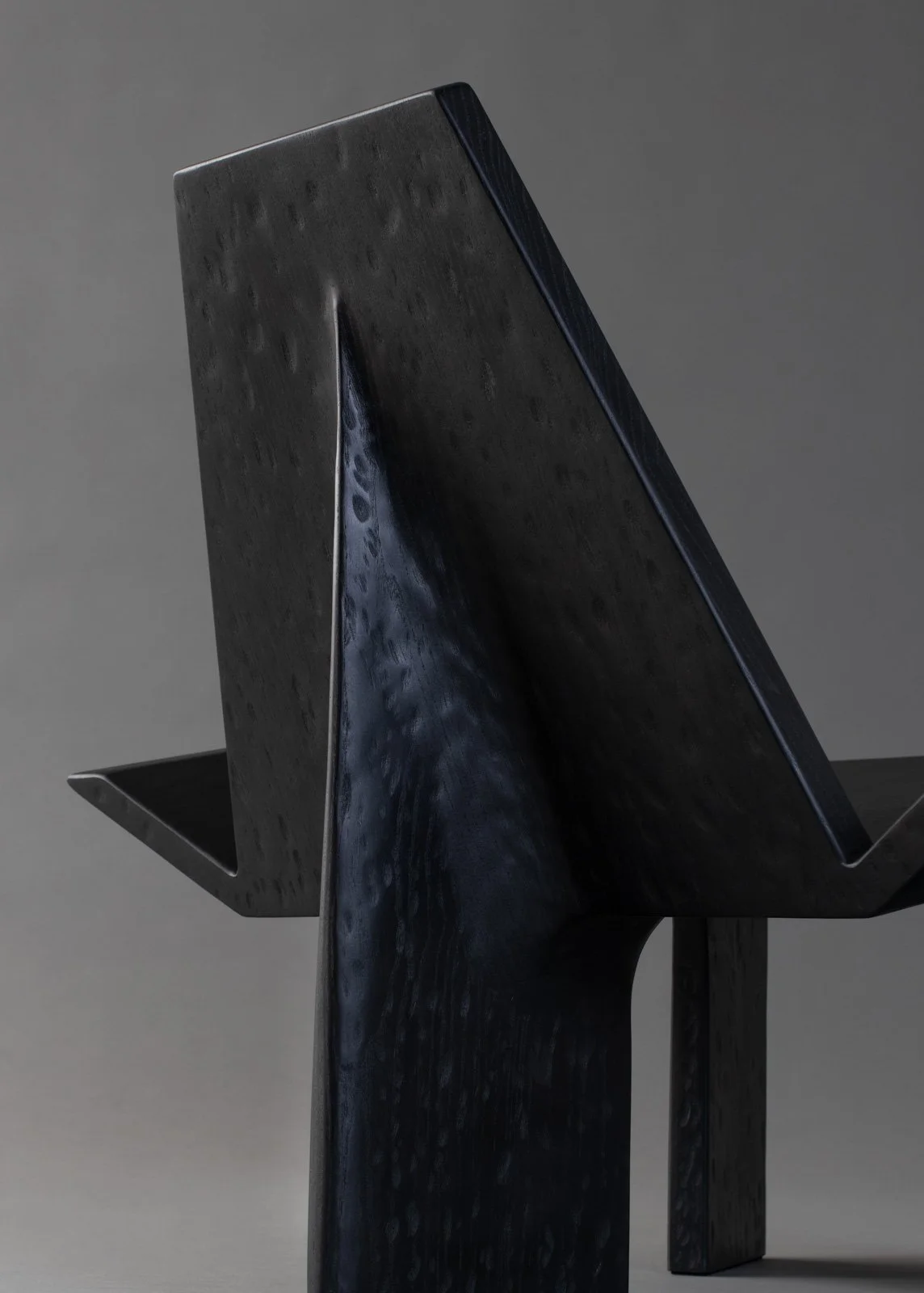 Une sculpture moderne en bois sombre avec une finition lisse, formant une structure abstraite.
