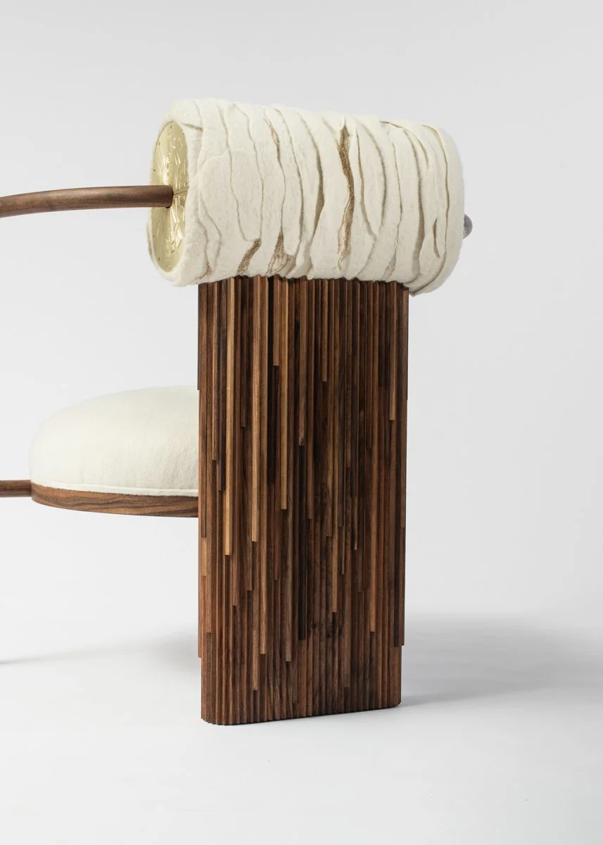 Chaise avec dossier en bois, assise en rembourrage beige, et un cylindre en tissu blanc avec des motifs marron, posé sur un support en bois vertical. Fond blanc.