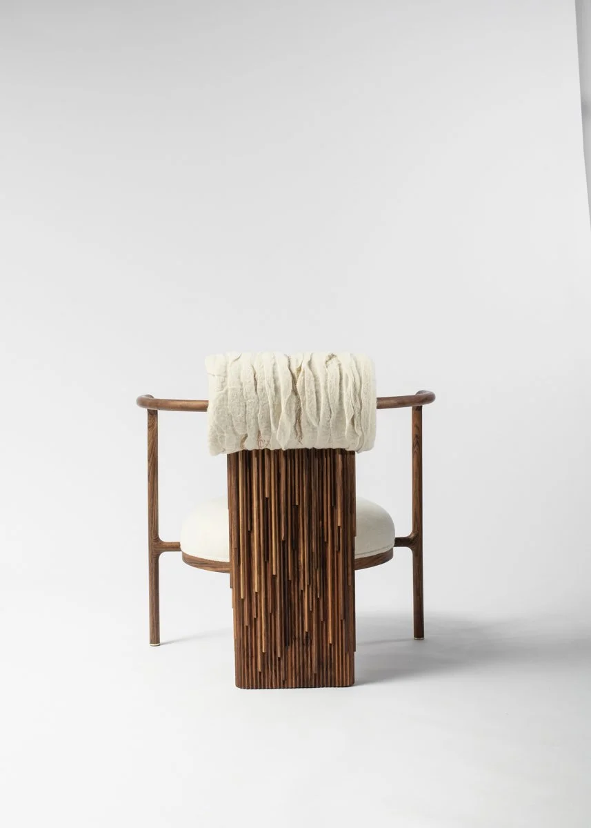 Une chaise en bois avec un coussin blanc et une pièce décorative en bois vertical au centre, avec un tissu blanc posé sur le dossier, sur fond blanc.