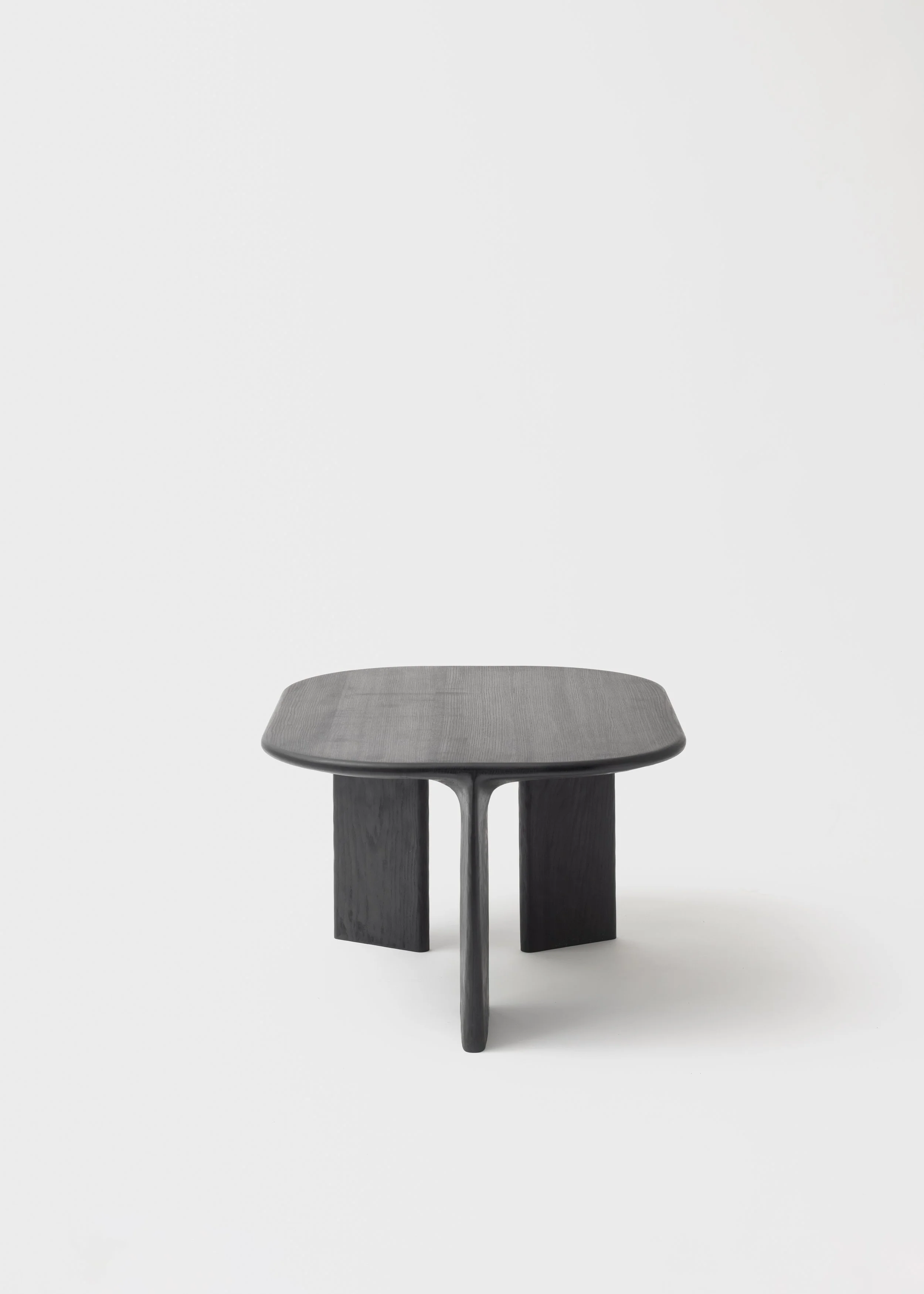 Un petit tabouret noir en bois avec un plateau rectangulaire. Ignorer l'arrière-plan blanc minimaliste.