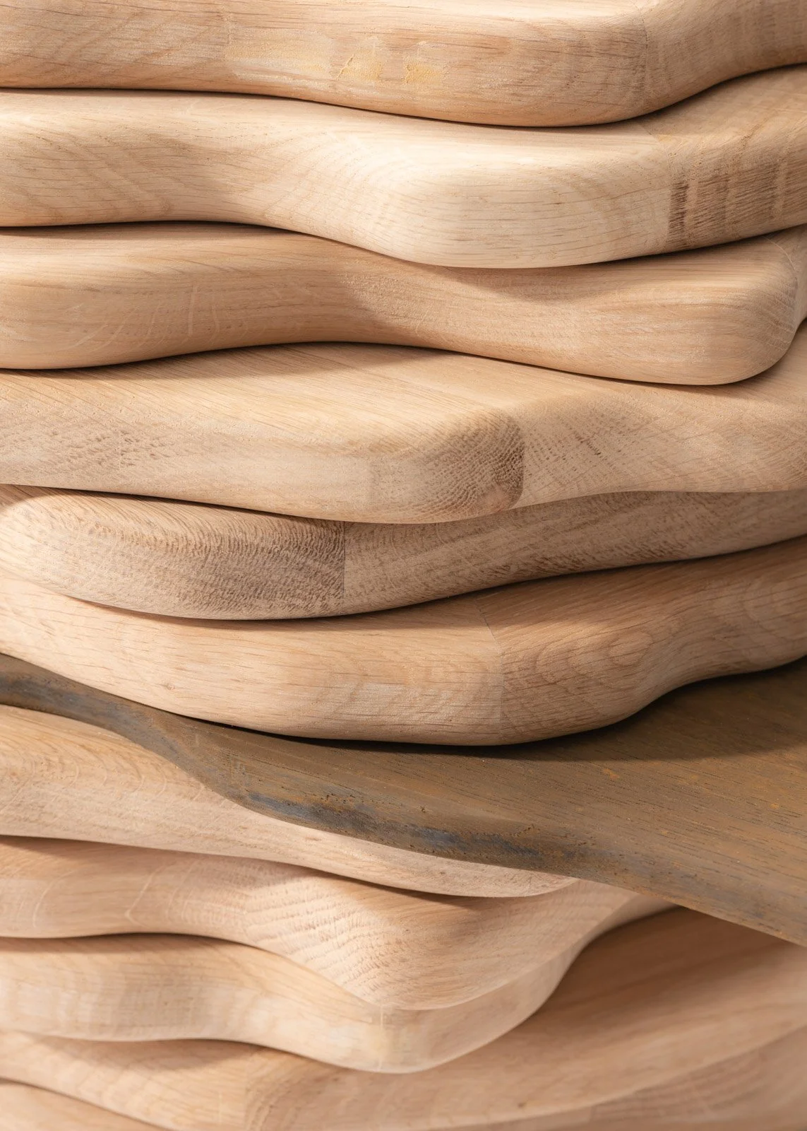 Pile de planches en bois clair avec des surfaces lisses et courbées.