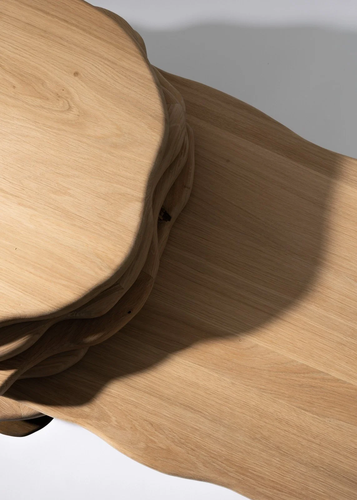 Une image de plusieurs planches de bois empilées, créant une ombre contrastée sur une surface blanche.
