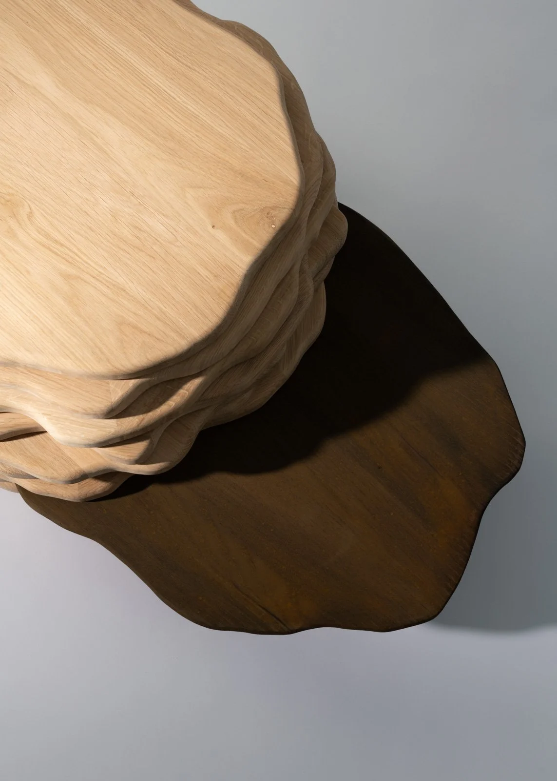 Une table basse en bois, empilées les unes sur les autres, avec une variation de couleurs allant du clair au foncé.