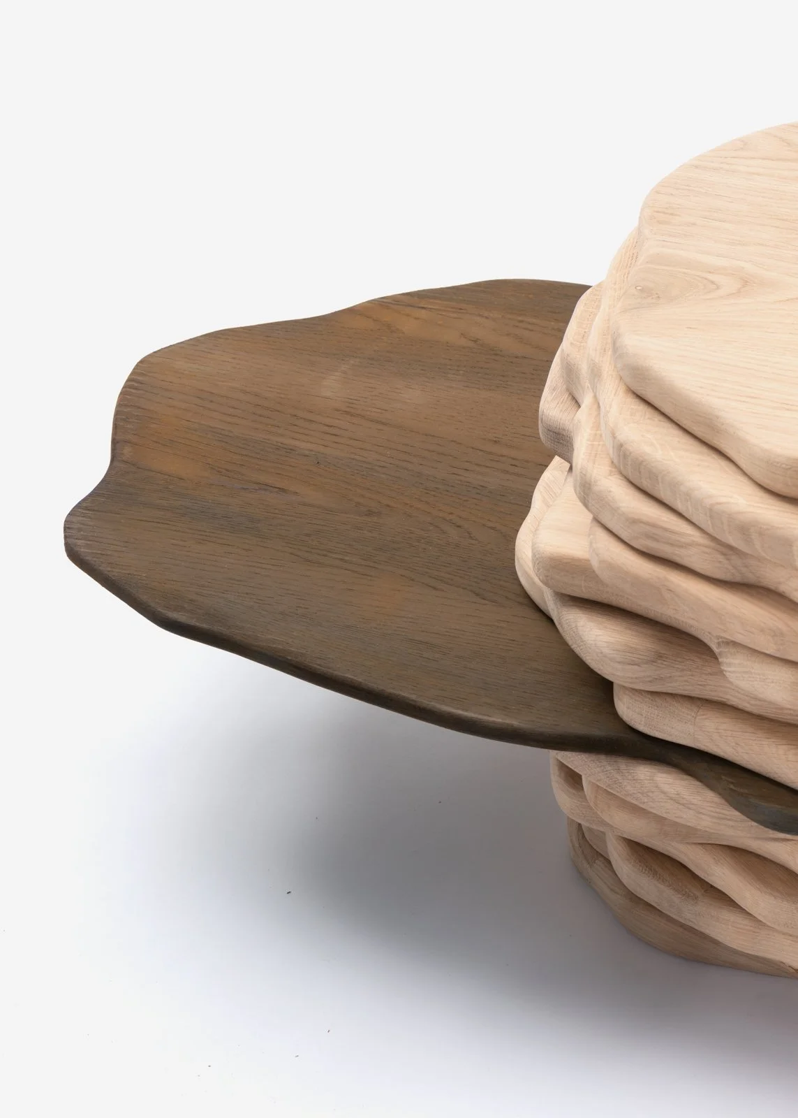 Une pile de bols en bois de différentes teintes, placés sur une surface blanche.
