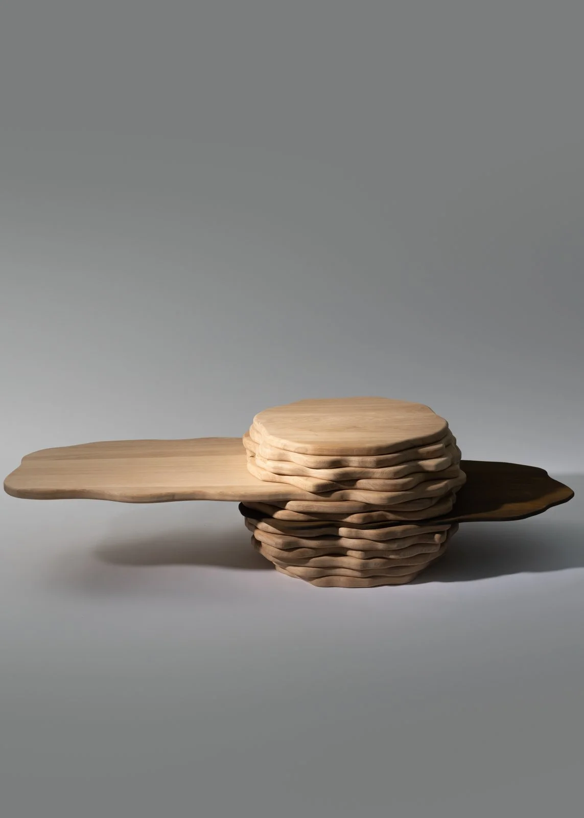 Une pile de planches en bois de différentes formes et tailles, disposées sur un fond gris