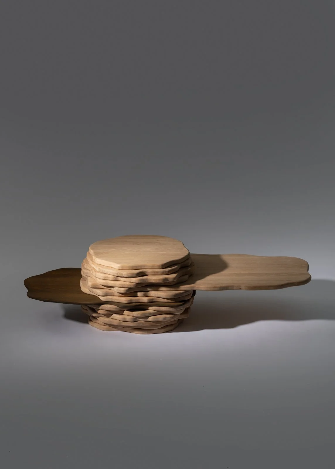 Une sculpture en bois composée de plusieurs pièces plates empilées, avec une pièce longue et Plate qui traverse horizontalement le sommet de la pile.