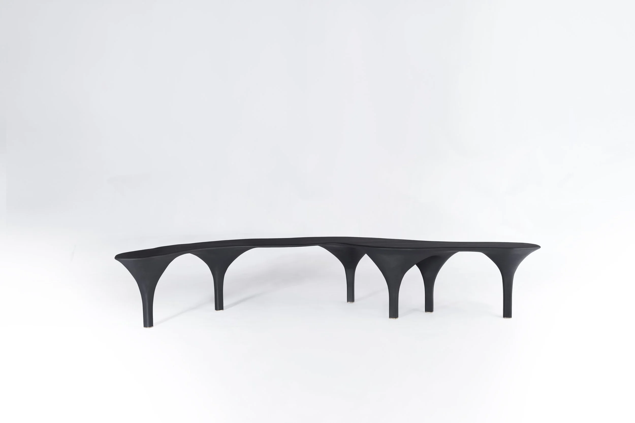Une table moderne noire avec des arches comme supports, placée sur un fond blanc
