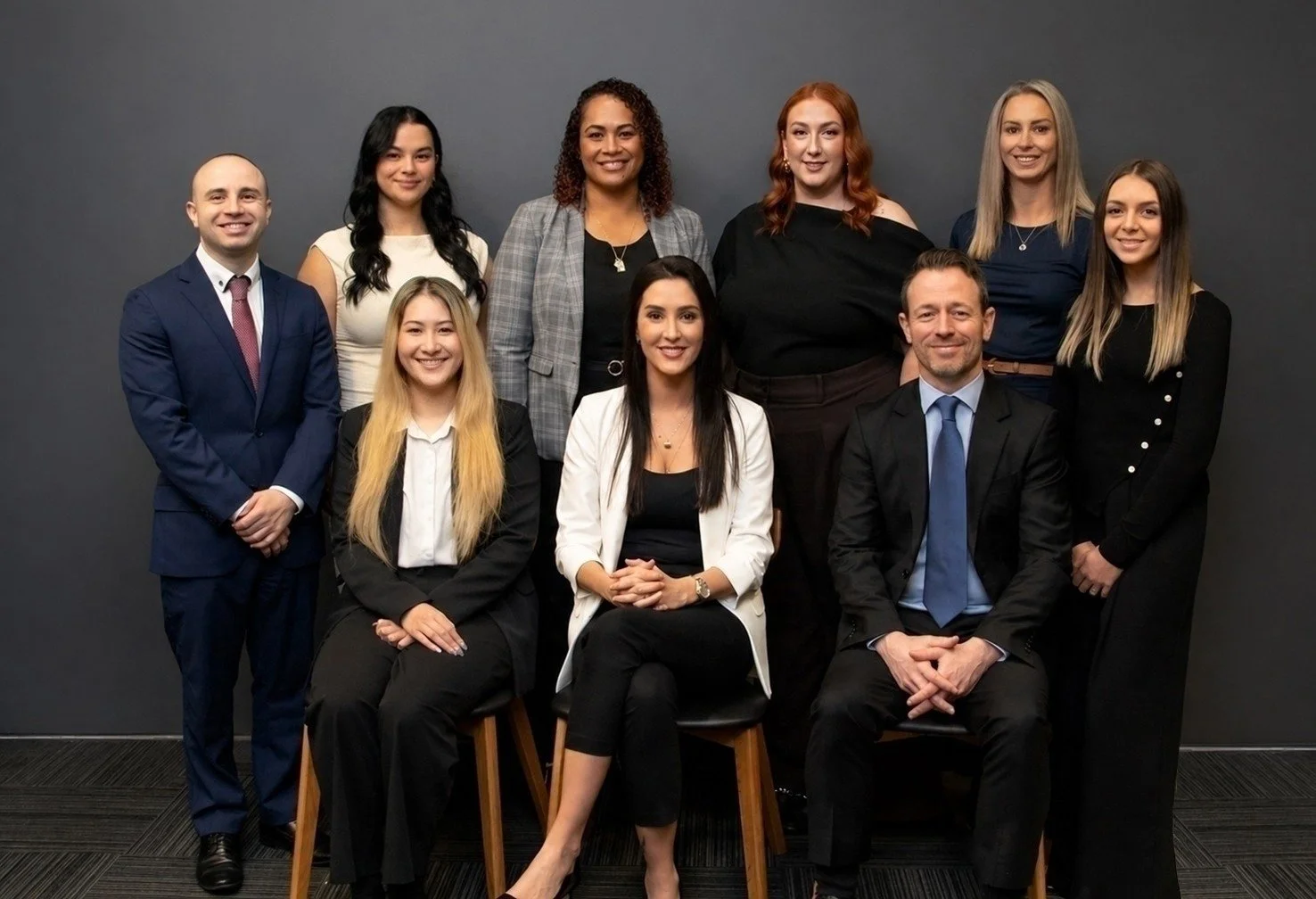 Integrate Recruitment team, six women and four men, dressed in business attire, posing against a dark gray background