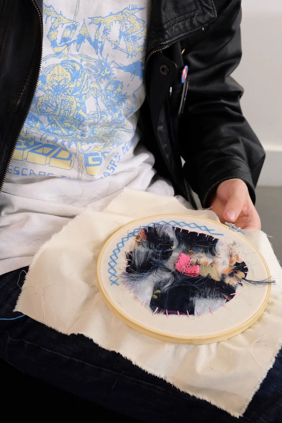 Workshop participant stitching reclaimed fabrics and feathers in an embroidery hoop.