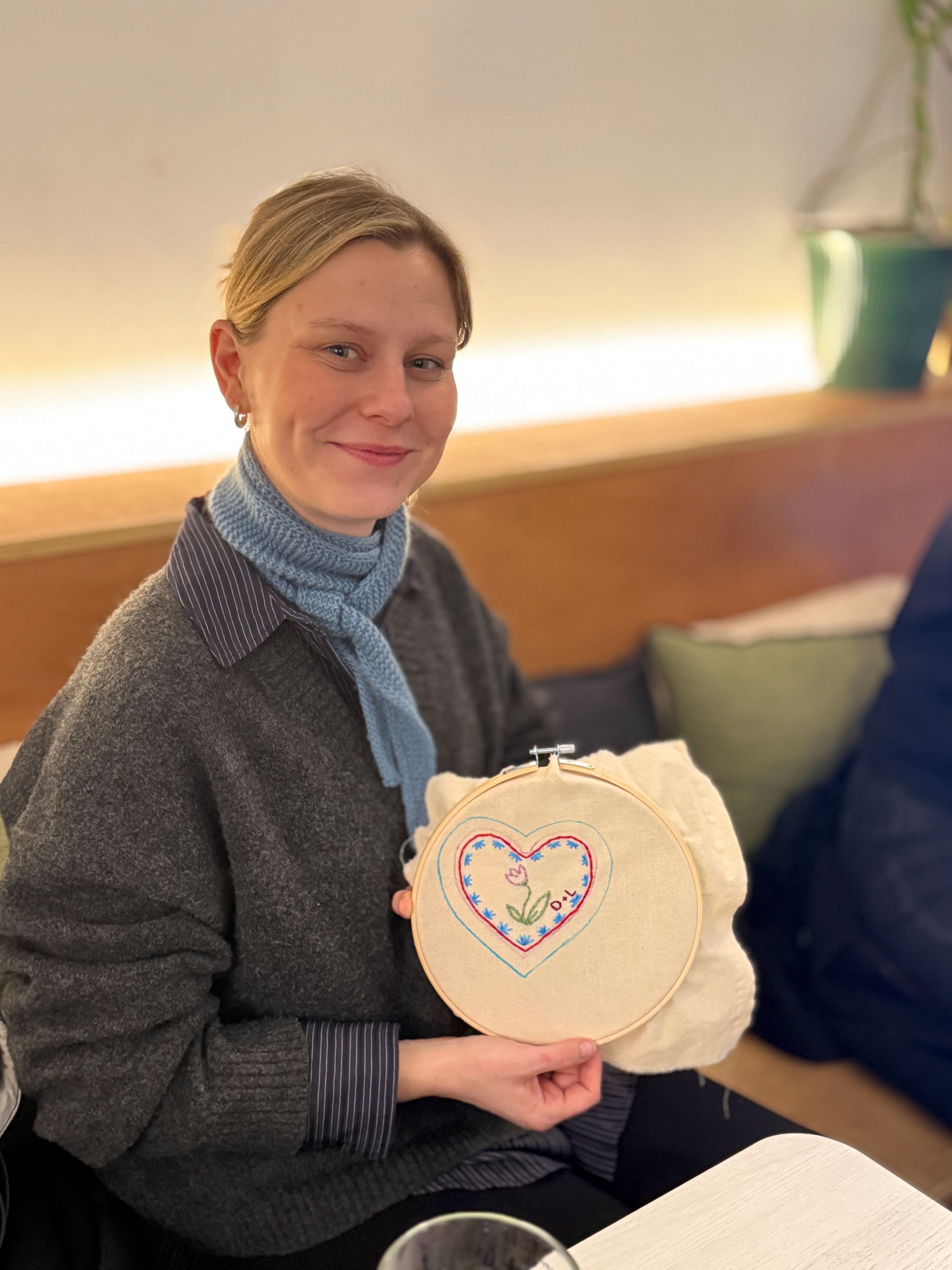 Participant holding an embroidered heart design in an embroidery hoop.