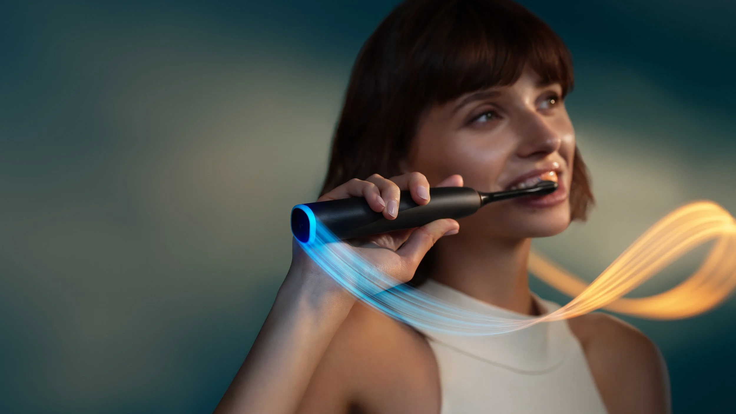 Woman brushing her teeth with a black Philips Sonicare electric toothbrush, surrounded by flowing blue and orange light trails against a soft teal background. |

Philips Sonicare