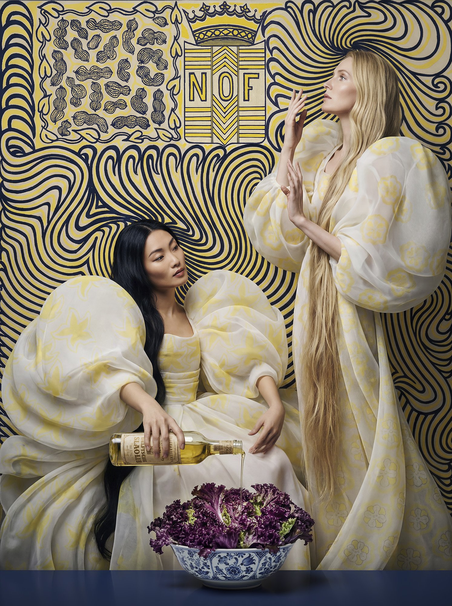 Fashion editorial scene inspired by Jan Toorop's poster print with two women in flowing white dresses beside a bowl of red lettuce, styled around a vintage Delftsche Slaolie bottle against a bold blue and yellow graphic backdrop.