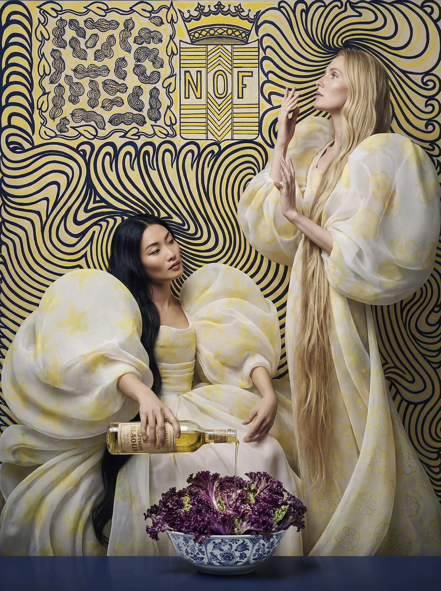 Fashion editorial scene inspired by Jan Toorop's poster print with two women in flowing white dresses beside a bowl of red lettuce, styled around a vintage Delftsche Slaolie bottle against a bold blue and yellow graphic backdrop.