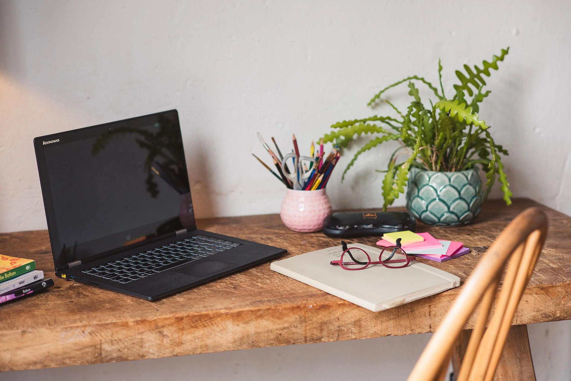 Desk ready for a reflective mentoring session with a notebook, pens and glasses on a desk
