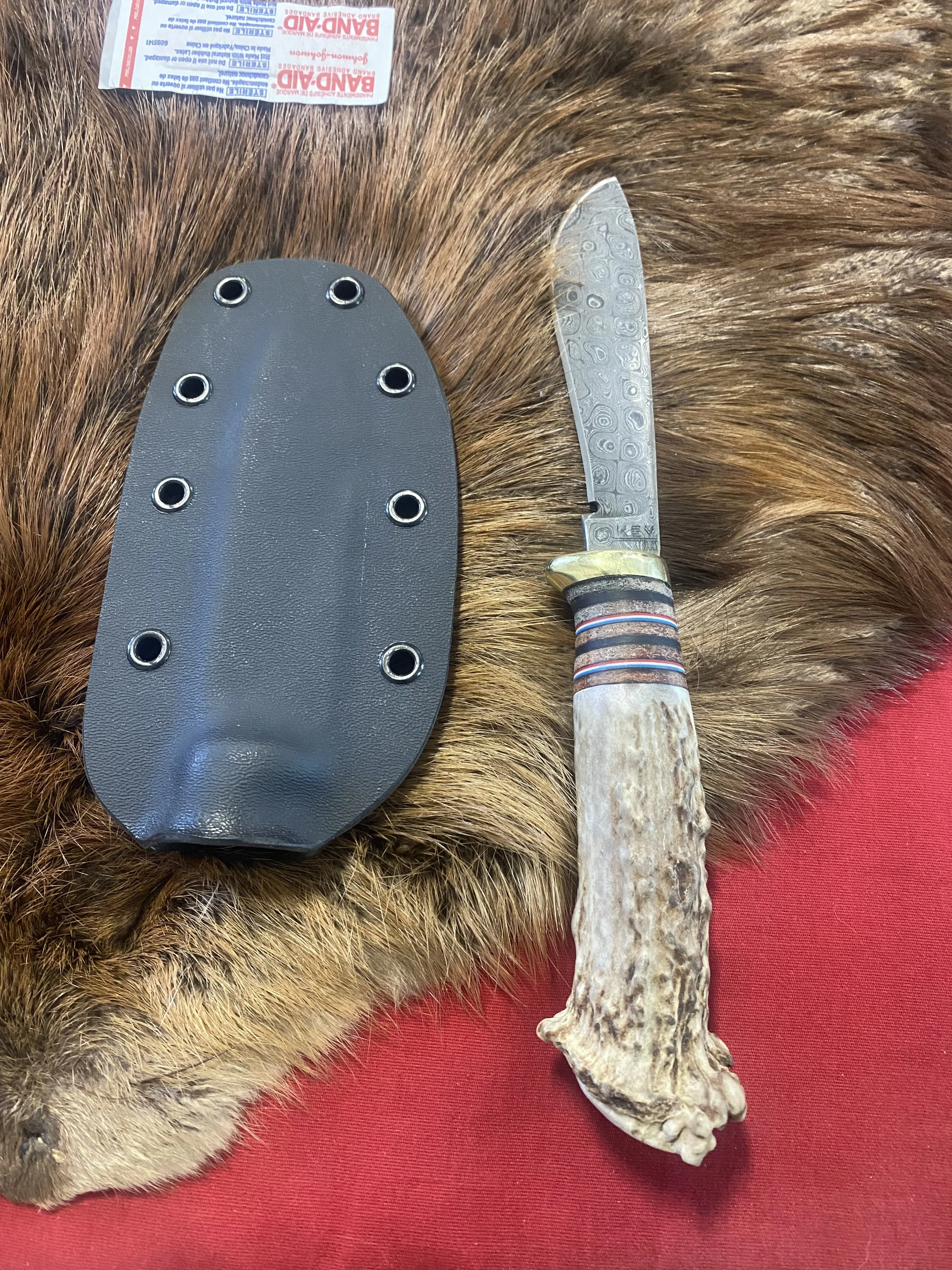 Raindrop Damascus with brass guard stacked leather, g-10 spacers and deer antler crown handle