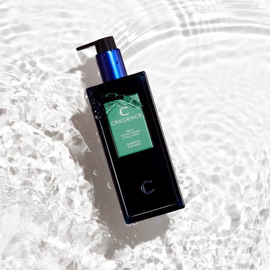 A blue bottle of Credence Fresh Shampoo for Men floating on water with a blue pump dispenser