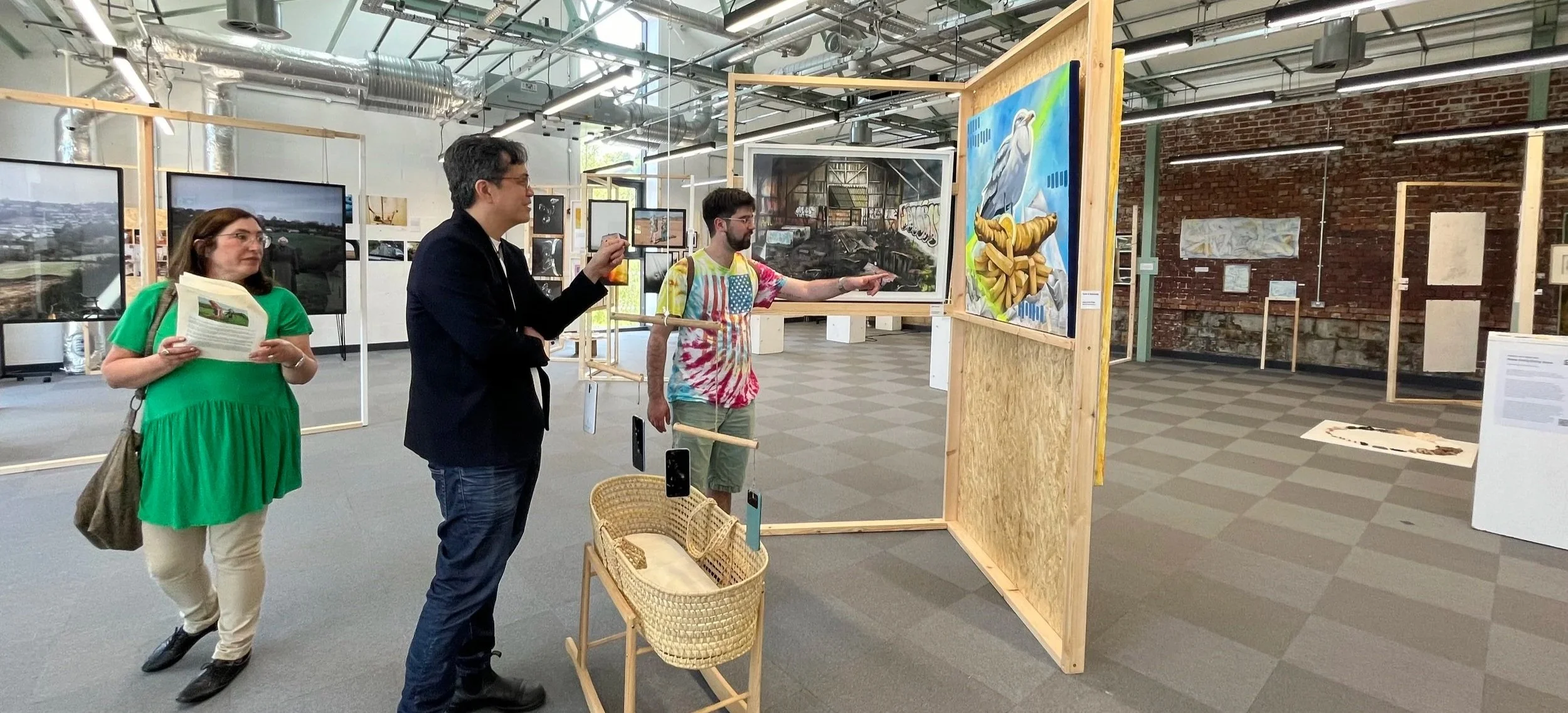 Visitors viewing and discussing a colourful seagull mixed media painting by wildlife artist Sam B. Kennedy at Fringe Arts Bath Festival 2026. Contemporary animal artwork exhibited at Newark Works, Bath.