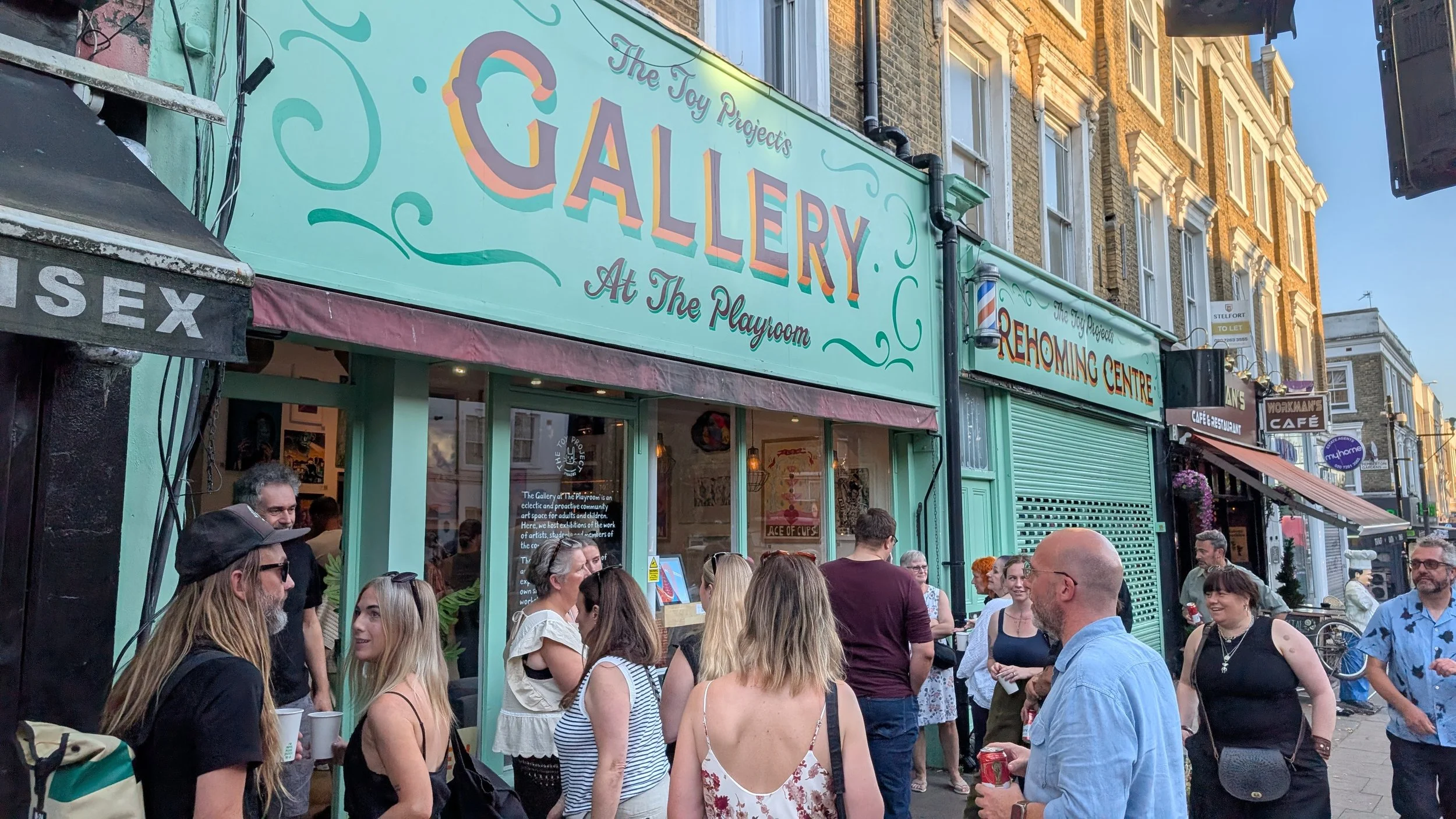 Busy opening night outside The Gallery at the Playroom in Archway, London, with visitors spilling onto the street for the Everyday Magic contemporary art exhibition featuring emerging artists.