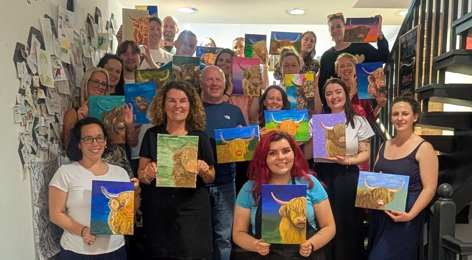 Participants proudly holding their completed Highland cow paintings at a sold-out Paint & Sip workshop with Guildford artist Sam B. Kennedy at Art & Grind, a fun acrylic painting event in Surrey.