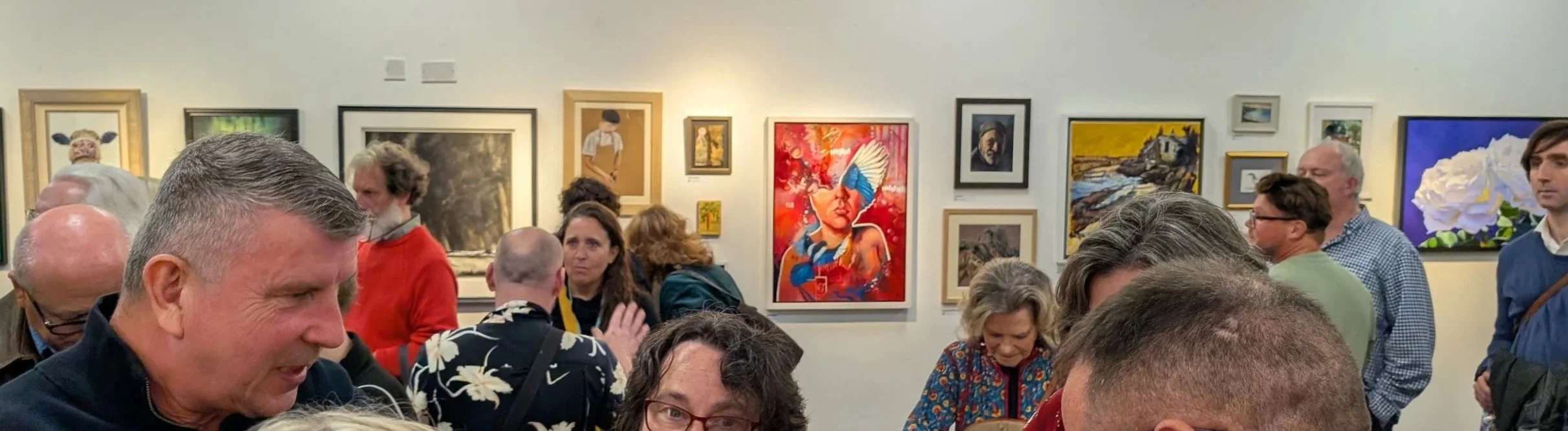SAA Artist of the Year 2026 finalists exhibition at Cass Art Kingston, featuring a wall of contemporary paintings and drawings with visitors viewing the shortlisted artworks, including Fortune Flames by Surrey artist Sam B. Kennedy.