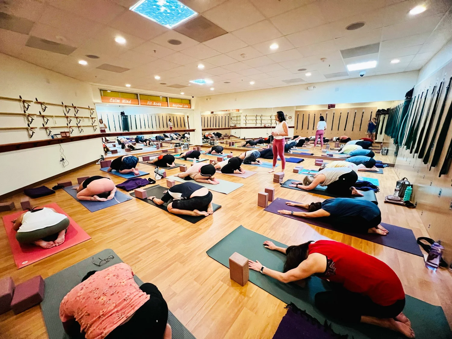 A teacher guiding a full class at Yoga Health Center