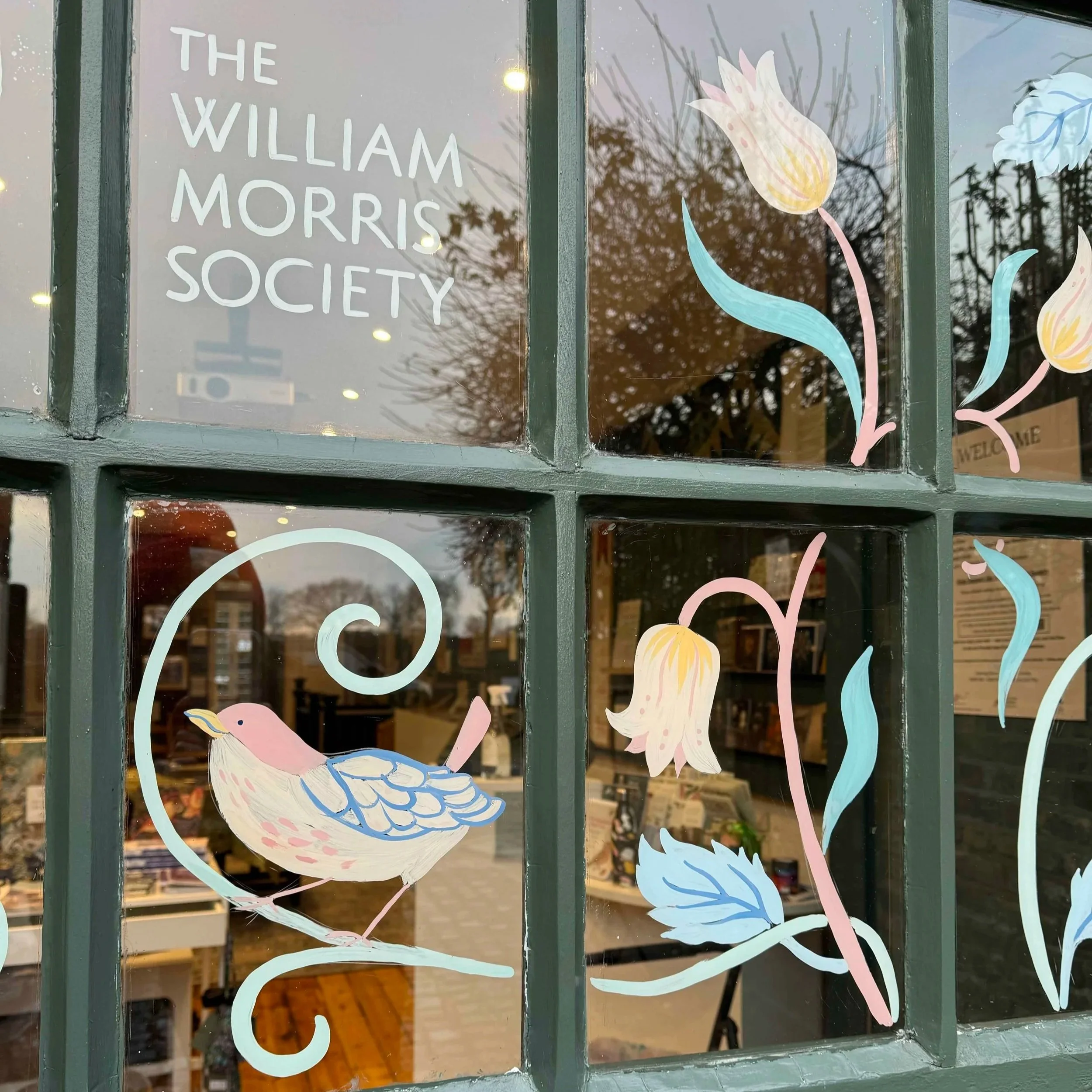 Close up image of a window mural showing a hand-painted bird and flowers