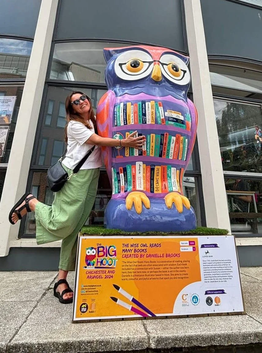 Danielle Brooks smiling and hugging a large owl she painted as part of the 2024 Big Hoot