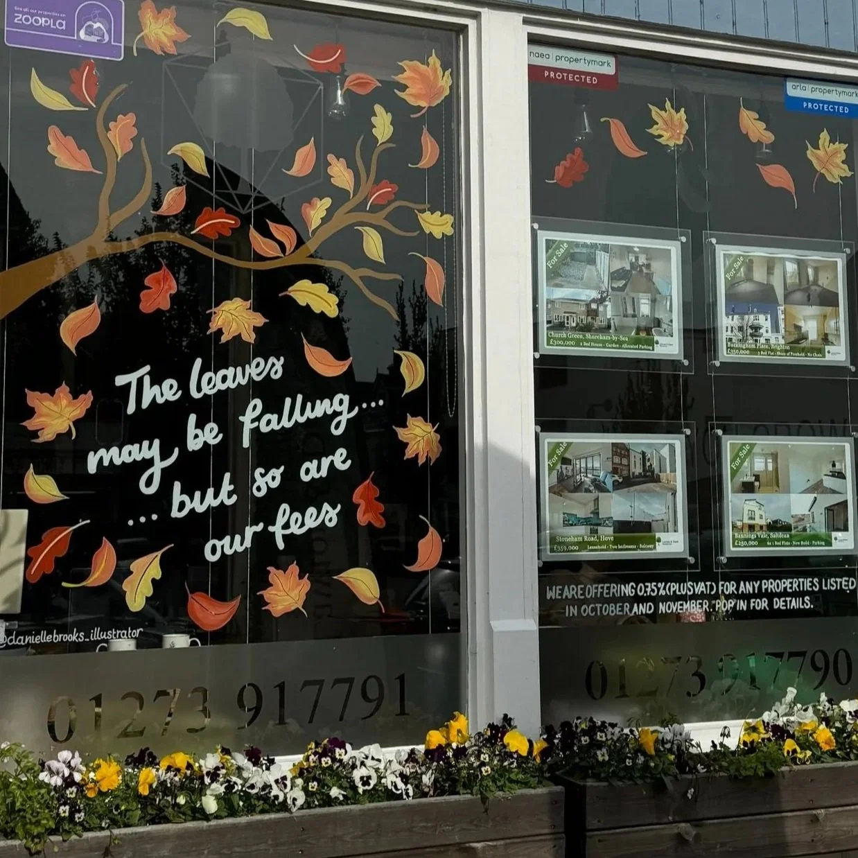 Hand-painted autumn tree window art in an estate agents window