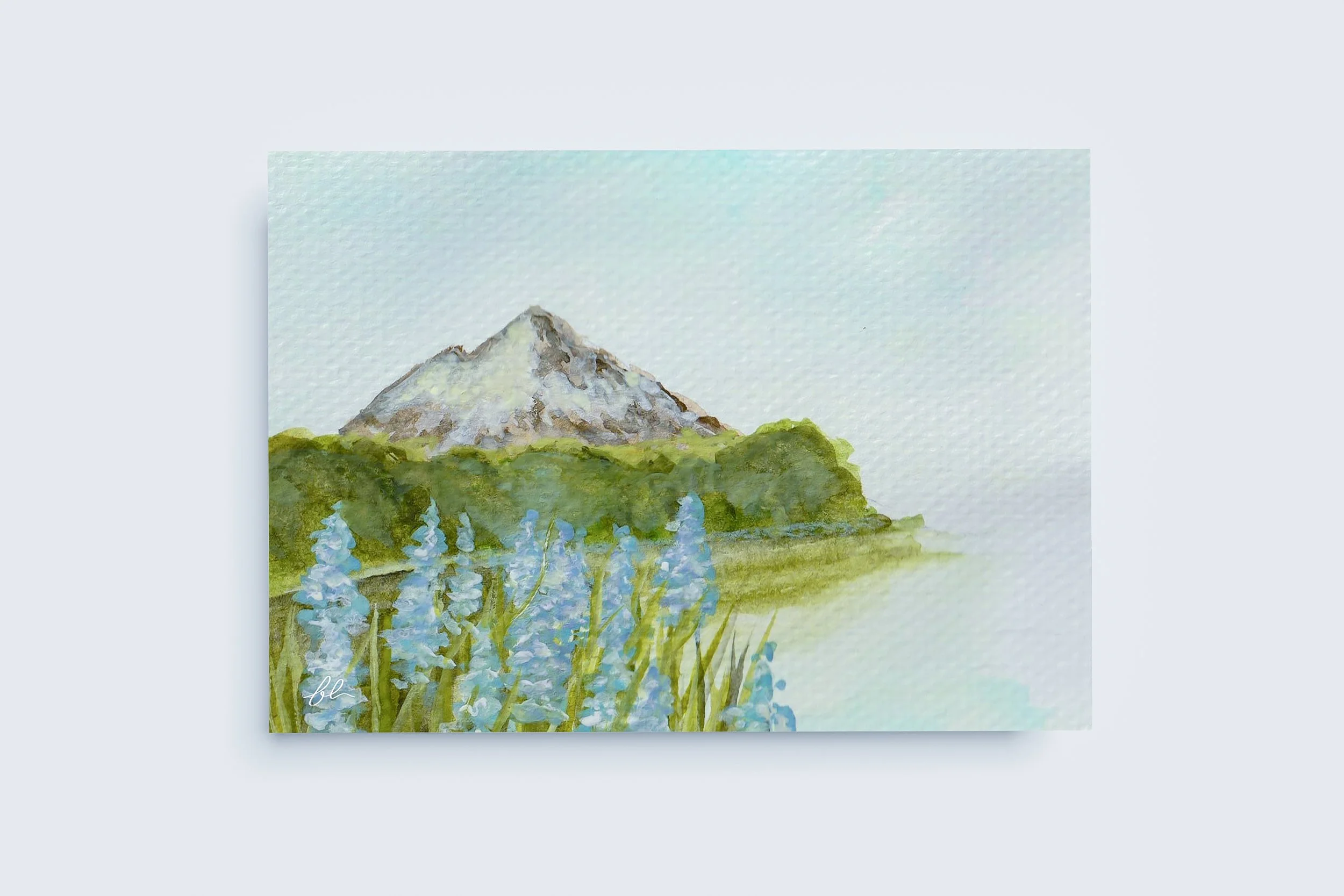 A tranquil mountain scene in muted watercolour tones, where gentle blooms and distant peaks create a sense of calm, balance, and quiet reflection.