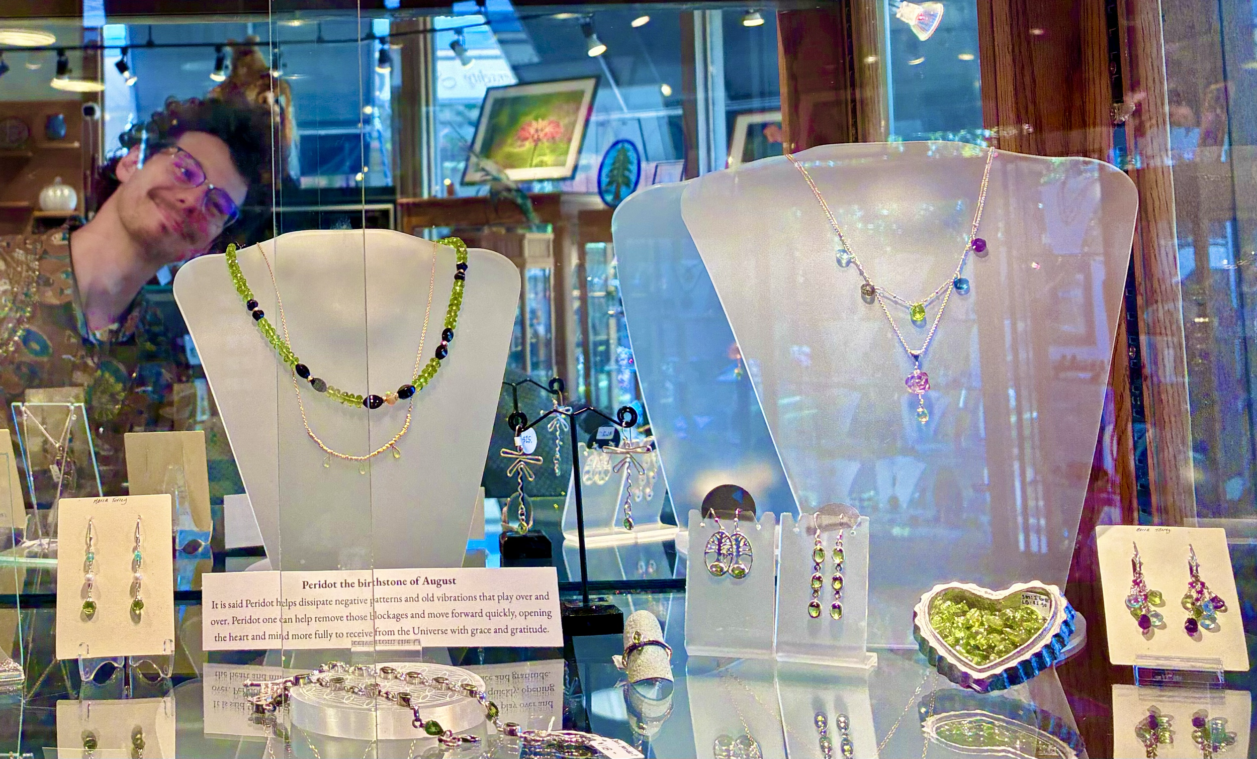 A section of our Peridot the birthstone of August shelf.  Local artisan Gabe Mellows is photo boming the shelf but we like him anyway since he designed the dragonfly earrings showcased on the shelf!