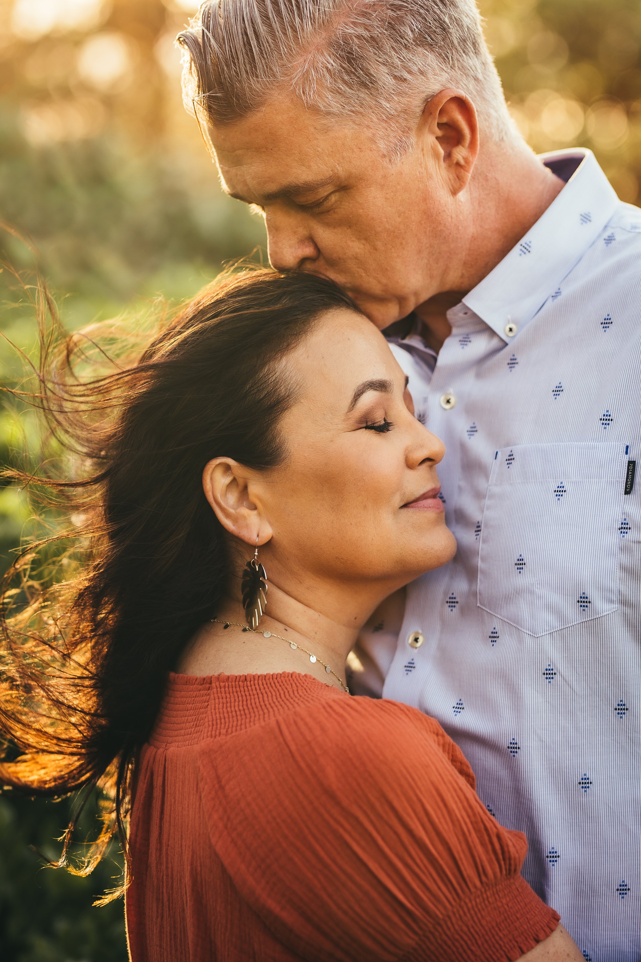 closeup of man kissing woman's head while they embrace eachother