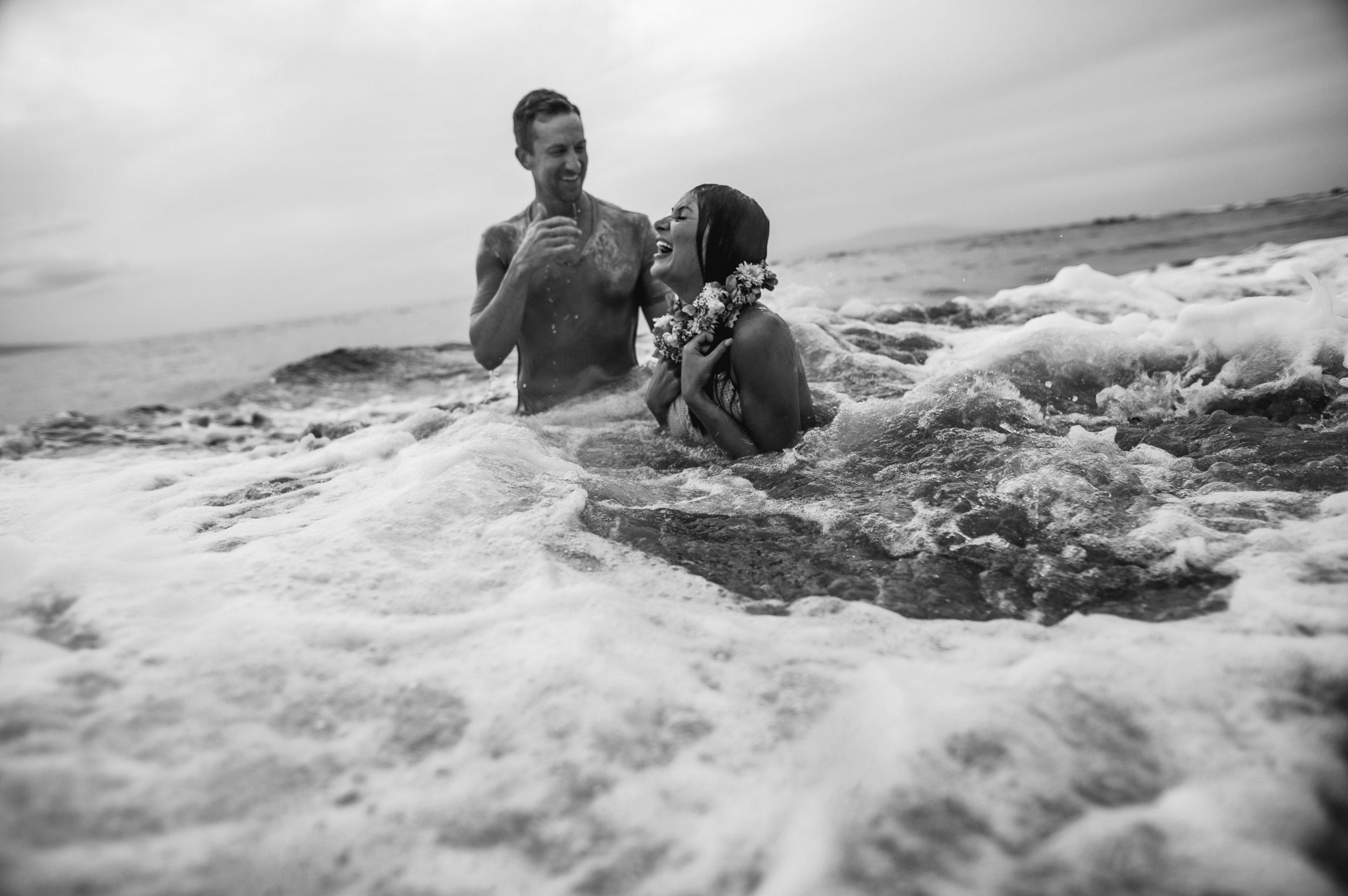 black and white photo of couple immersed in ocean laughing in maui