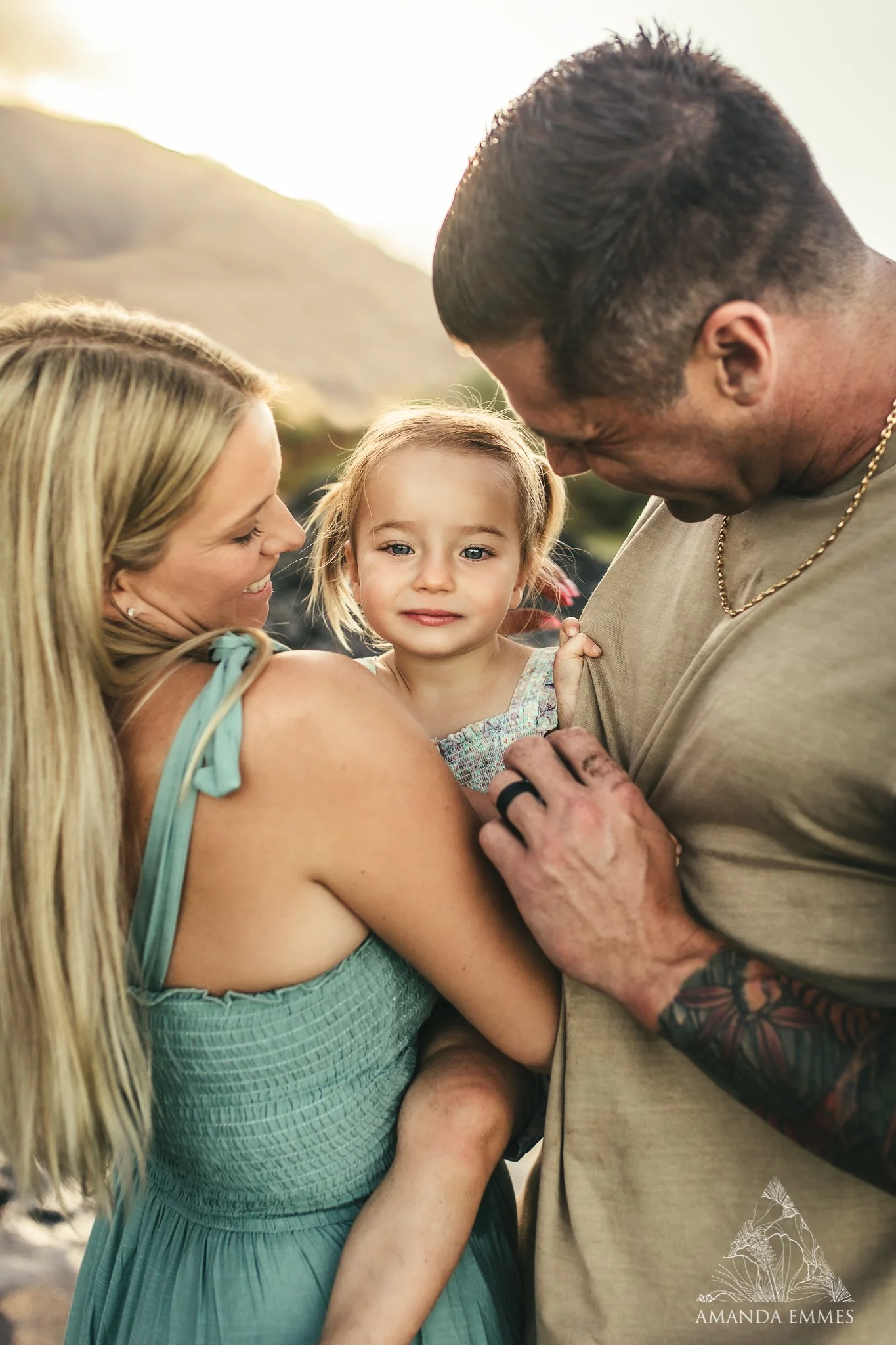Mother & father holding toddler daughter in middle while enjoying a sunrise family photo session on maui with amanda emmes
