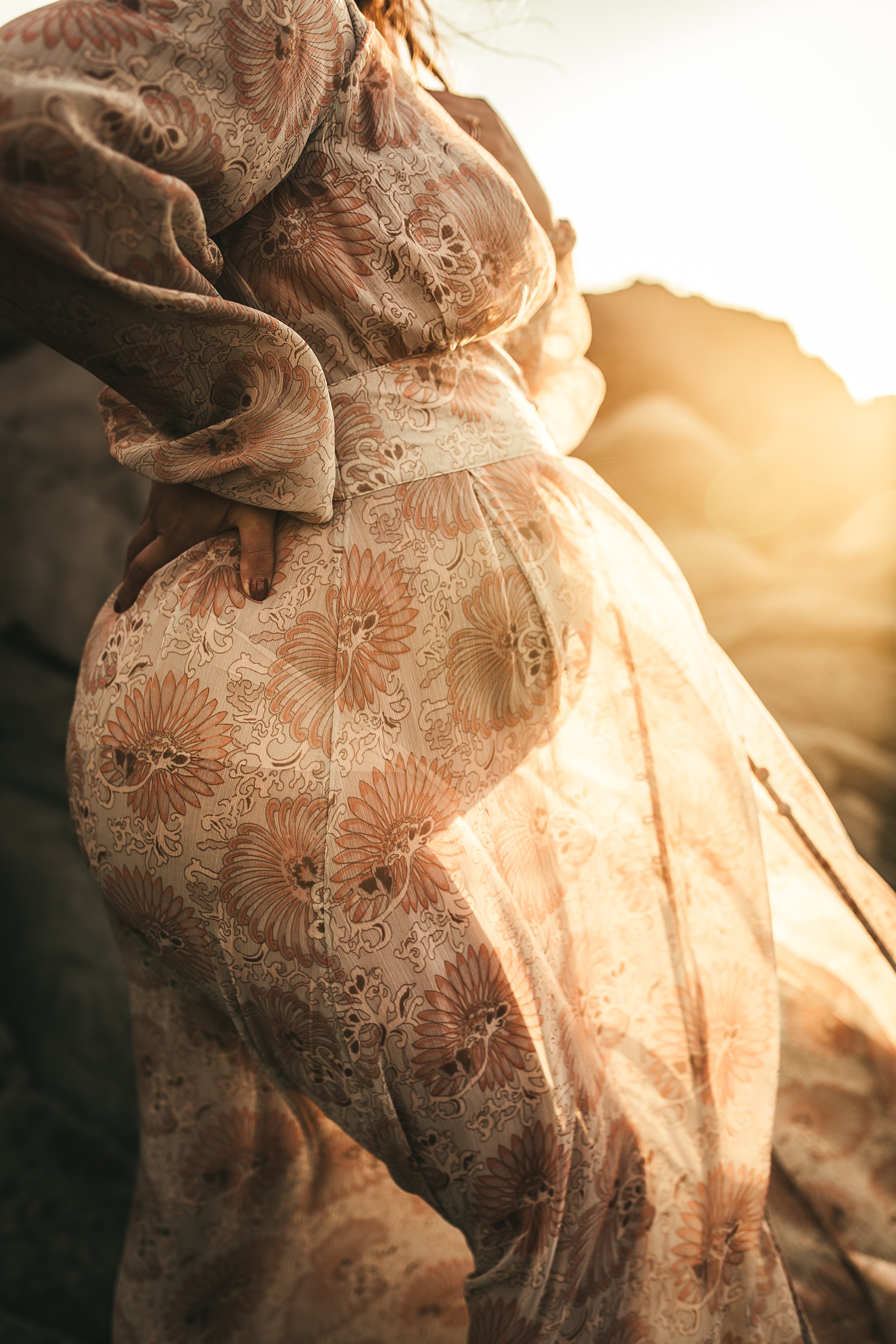 side view of pregnant woman's tummy in dress with sunlight shining behind her