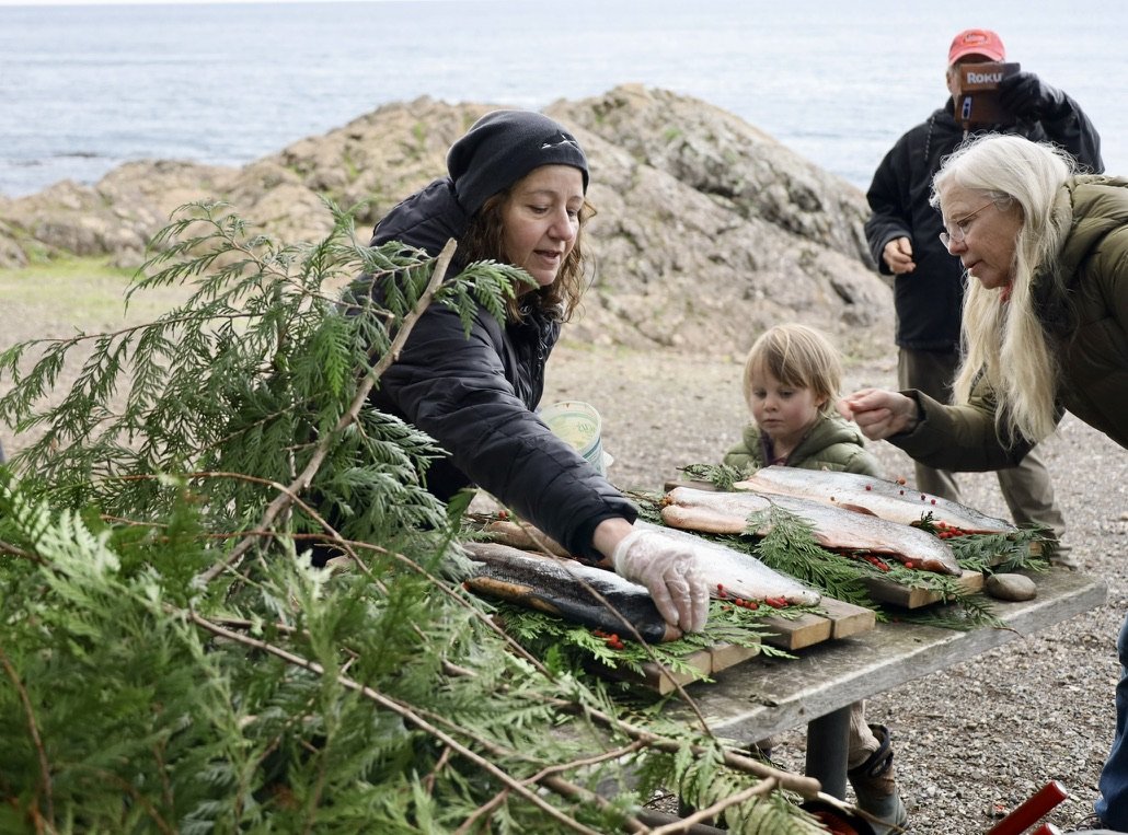    Cindy Hansen from Orca Network and volunteers decorate traditional Indigenous salmon memorial offerings. The offerings were given to the ocean in memory of Sk'aliCh'elh-tenaut and Ken Balcomb, an inspiring orca researcher. // Photo by Reid Hunter 