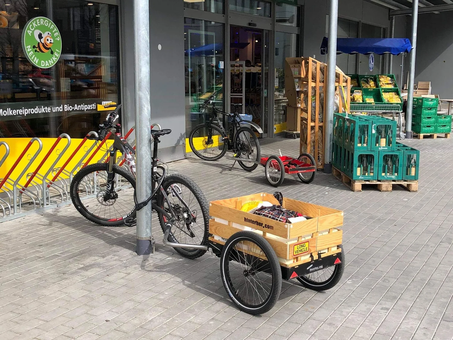 Fahrradanhänger mit Holzkiste vor einem Biomarkt