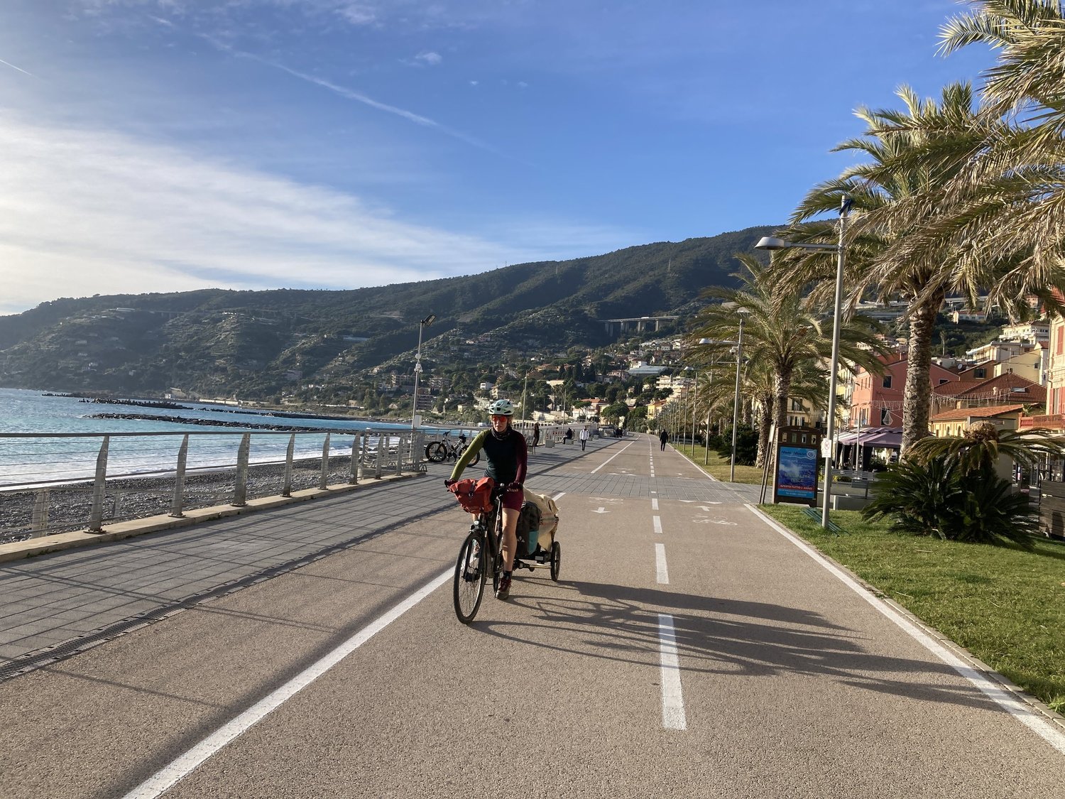 Radfahrer mit Faltrad und Hinterher Hmini auf einem Radweg am Meer
