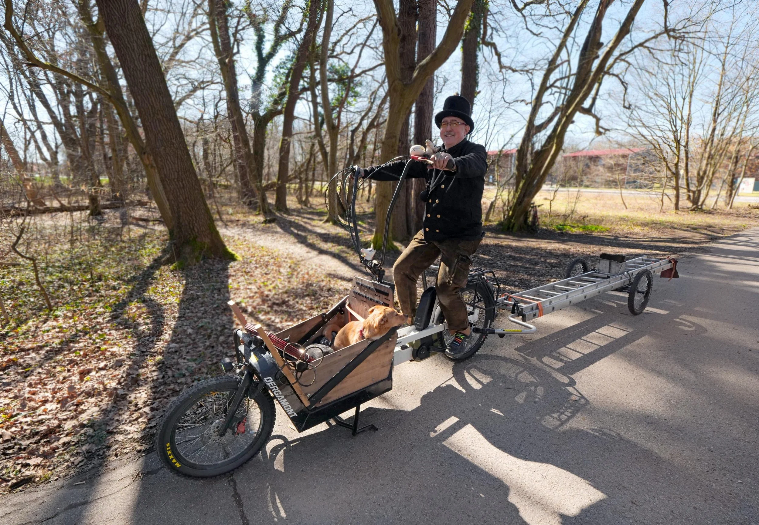 Ein Schornsteinfeger transportiert seine Leiter mit einem Fahrradanhänger