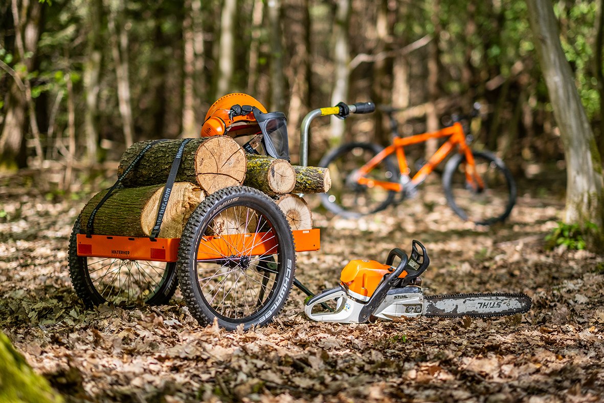Hinterher Hmax mit Brennholz und Motorsäge im Wald