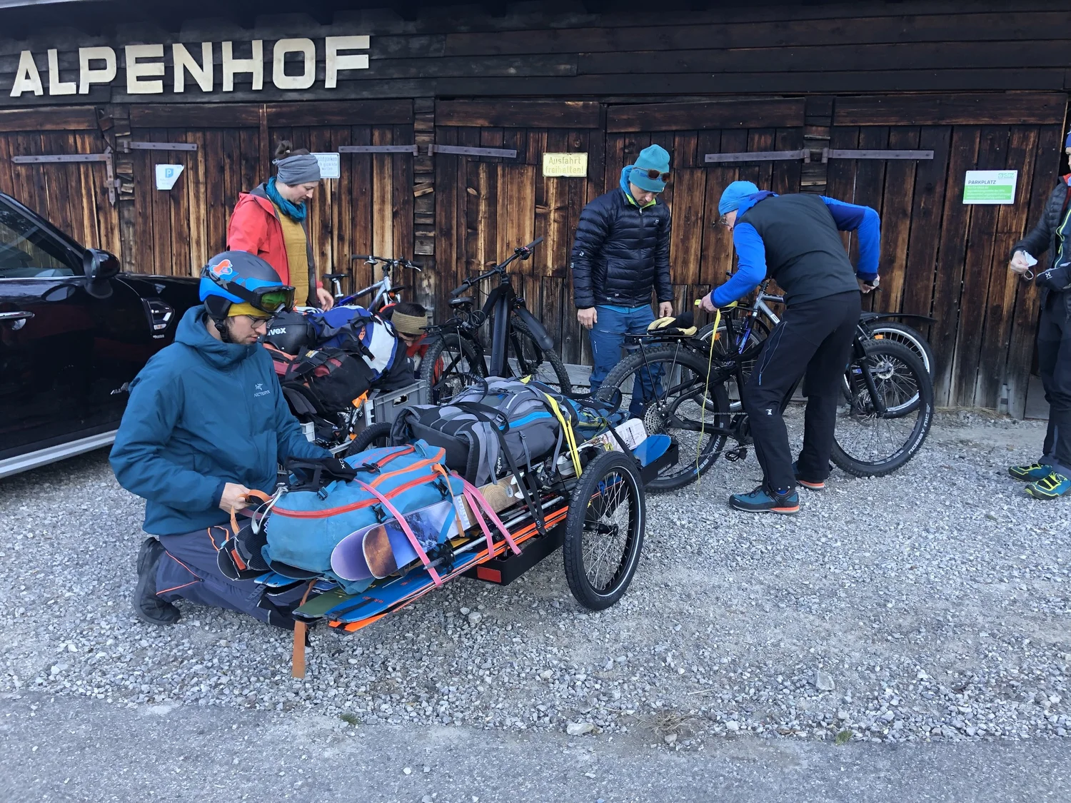 Jugendgruppe mit Fahrrädern und zwei Hinterher-Anhängern vor einem Bahnhof im Winter