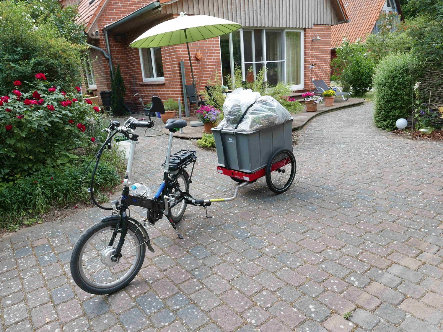Hinterher Hmax light mit Eurobox und Mörtelwanne voller Grüngut vor einem Haus