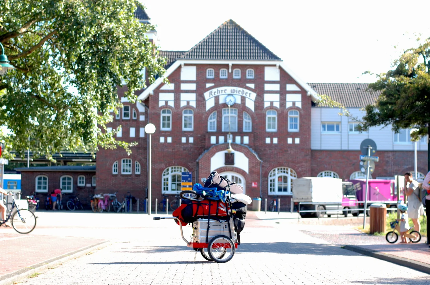 Hinterher Hmini mit Reisegepäck als Handwagen vor dem Bahnhof Wangerooge