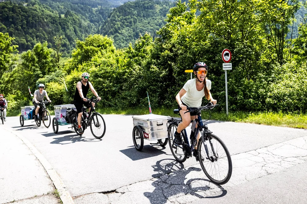 Gruppe auf Radtour mit Hinterher-Anhängern und Aluboxen in den Bergen