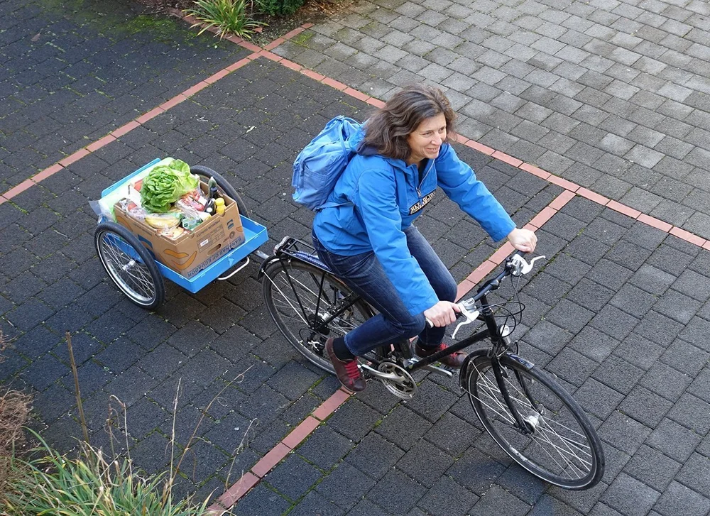 Radfahrerin mit Einkäufen auf dem Fahrradanhänger