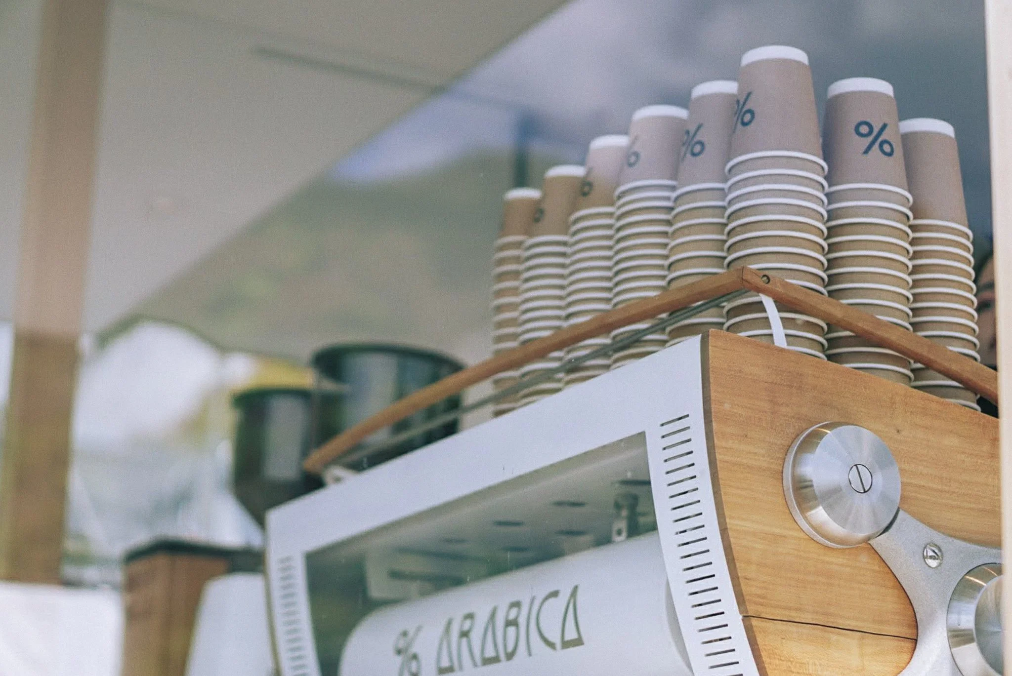 Stacked paper cups with percentage symbols on a wooden and metal coffee machine