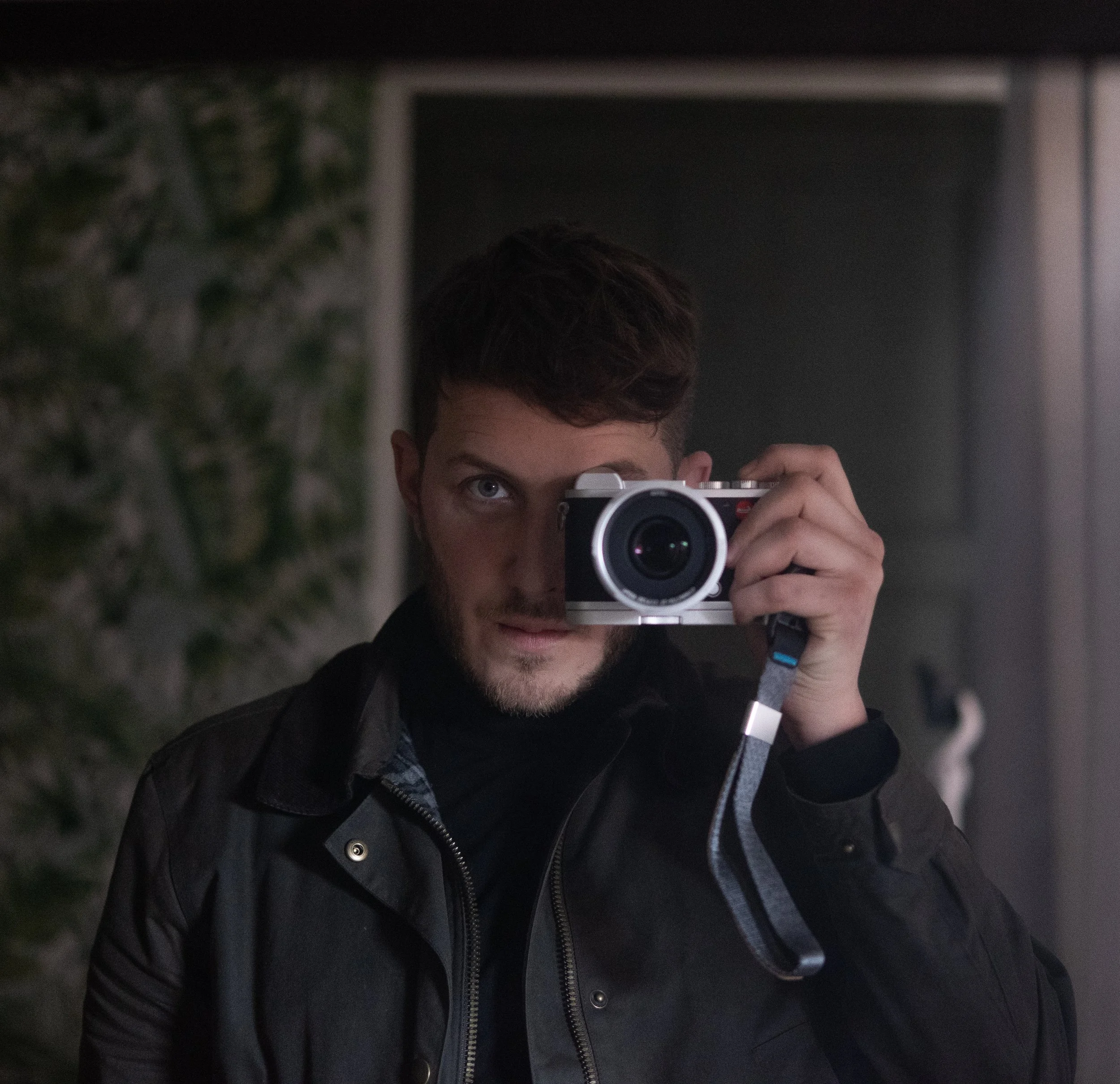A photographer looks into a mirror taking a photo of himself