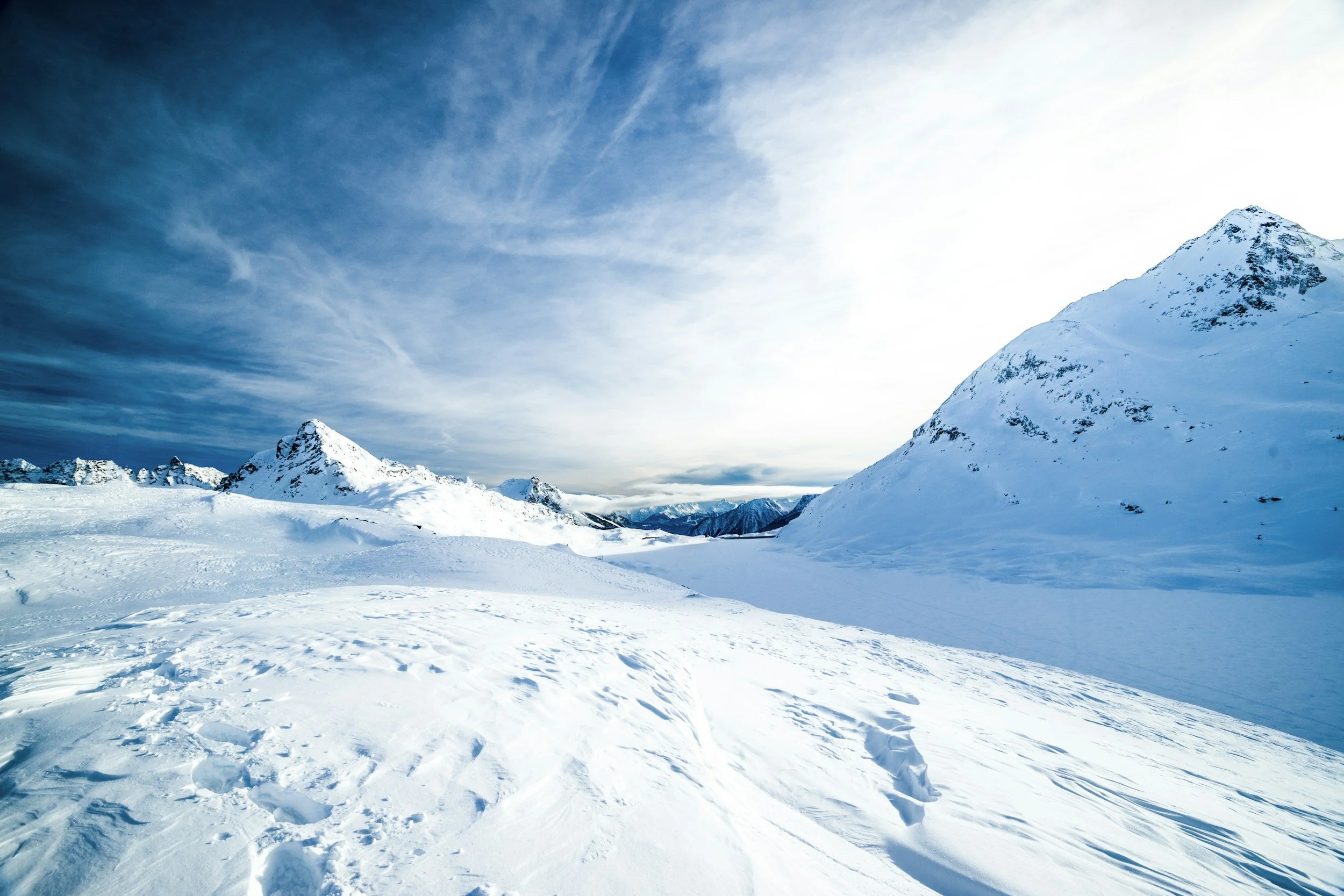 Snow-covered mountains and a cloudy sky in a polar landscape.